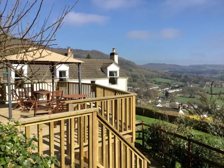 Raised wooden deck with outdoor tables and chairs overlooking Llandogo and the Wye Valley at Bank Cottage