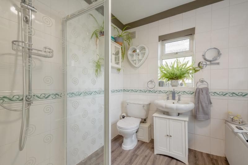 Coastal Bungalow with Decked Garden, Kinmel Bay, North Wales 6 Bathroom with a glass shower enclosure, toilet, pedestal basin with cupboard below and houseplants
