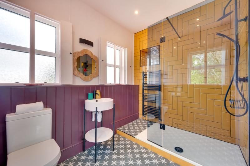 Colourful Cinema House near Craster, Northumberland 15 Bathroom with purple panelling, pedestal basin and walk-in shower with yellow herringbone tiles