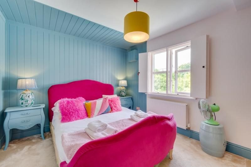 Colourful Cinema House near Craster, Northumberland 12 Blue panelled bedroom with a bright pink velvet bed and fluffy cushions