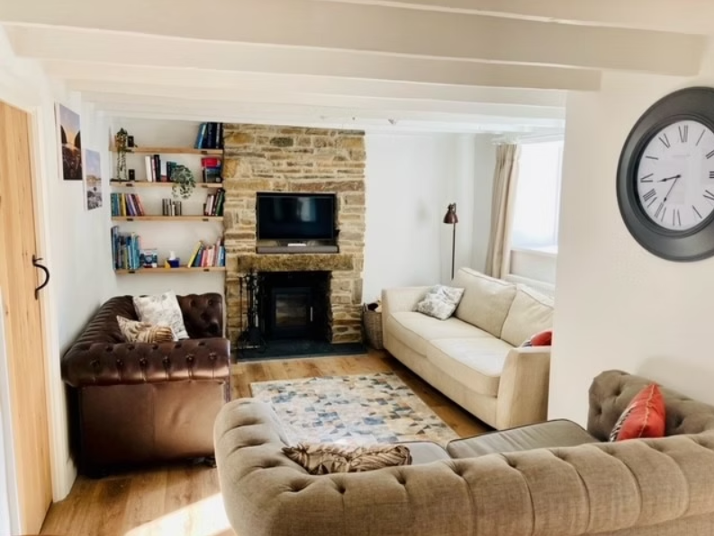 Boyne House, Pembrokeshire 5 Lounge at Boyne House with sofas, exposed ceiling beams and a log burner in a stone fireplace