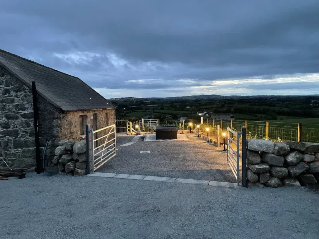 Stone cottage beside a gravel outdoor area with a hot tub and countryside views at Cabra Cottage