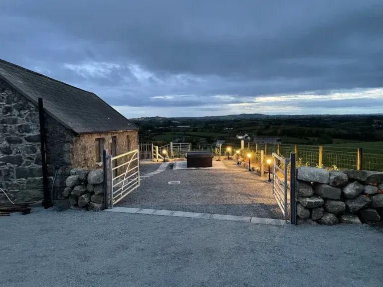 Stone cottage beside a gravel outdoor area with a hot tub and countryside views at Cabra Cottage