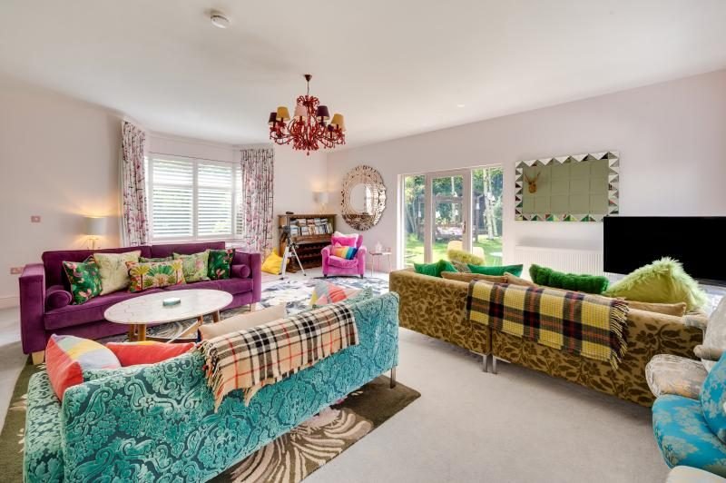 Colourful Cinema House near Craster, Northumberland 8 Lounge with purple, teal and olive sofas, tartan throws and a television