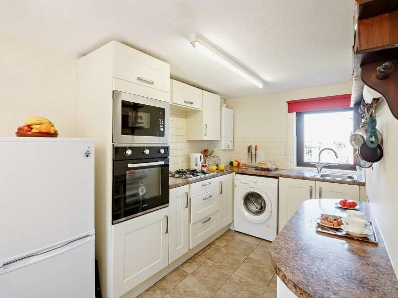 Kitchen with cream cabinets, a built-in oven and microwave, washing machine and breakfast counter