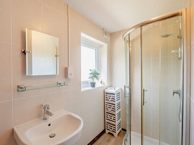 Shower room with a curved glass shower enclosure, white basin and tiled walls