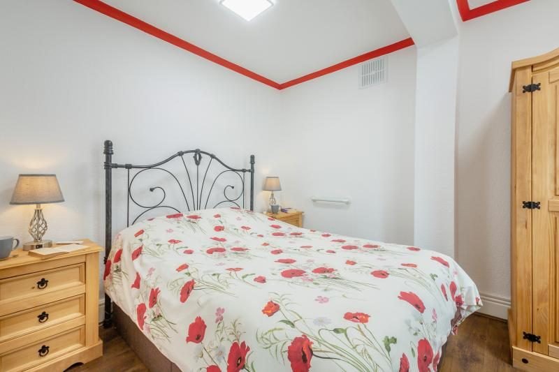 Coastal Bungalow with Decked Garden, Kinmel Bay, North Wales 5 Bedroom with a double bed, ironwork headboard, poppy print bedding, pine bedside chests and a wardrobe