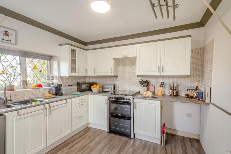 Coastal Bungalow with Decked Garden, Kinmel Bay, North Wales 3 Cream fitted kitchen with worktops, a freestanding double oven, a sink and a window