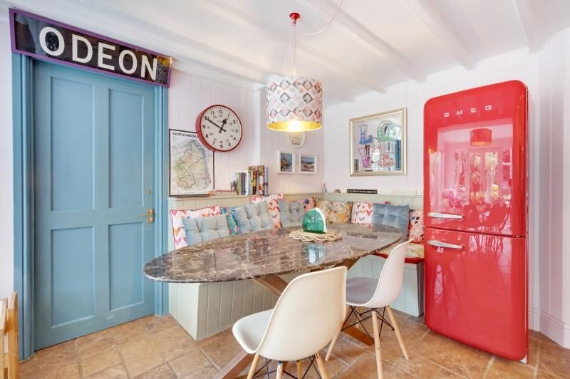 Colourful Cinema House near Craster, Northumberland 5 Bench seating and marble table beside a blue door and a red retro fridge freezer