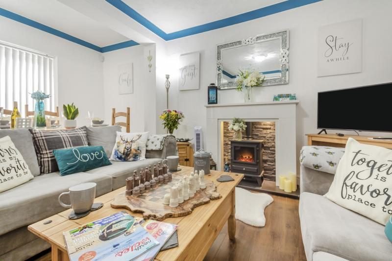 Coastal Bungalow with Decked Garden, Kinmel Bay, North Wales 1 Living area with grey sofas, a pine coffee table, an electric stove-effect fire and a television