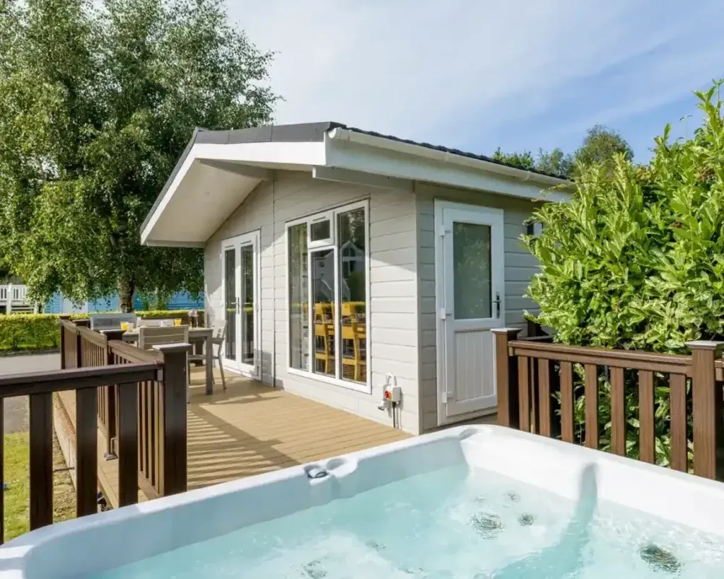 Shorefield Country Park, Milford-on-Sea, Hampshire 1 Outdoor hot tub beside a pale lodge with timber decking and an outdoor dining table