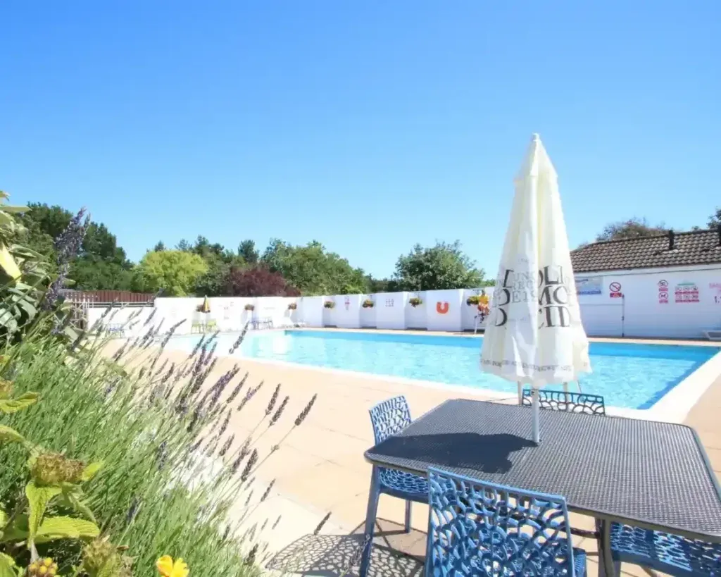 Shorefield Country Park, Milford-on-Sea, Hampshire 3 Outdoor swimming pool with a paved terrace, patio table, chairs and a closed parasol