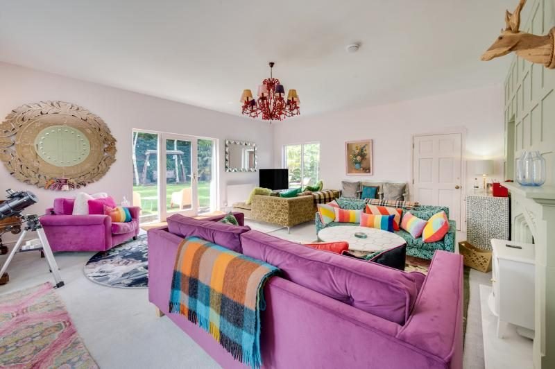 Colourful Cinema House near Craster, Northumberland 7 Large lounge with purple velvet sofa, patterned armchairs, red chandelier and doors to the garden