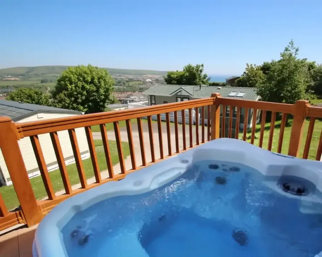 Swanage Coastal Park, Swanage, Dorset 2 Hot tub on a wooden deck overlooking holiday homes, hills and the sea at Swanage Coastal Park