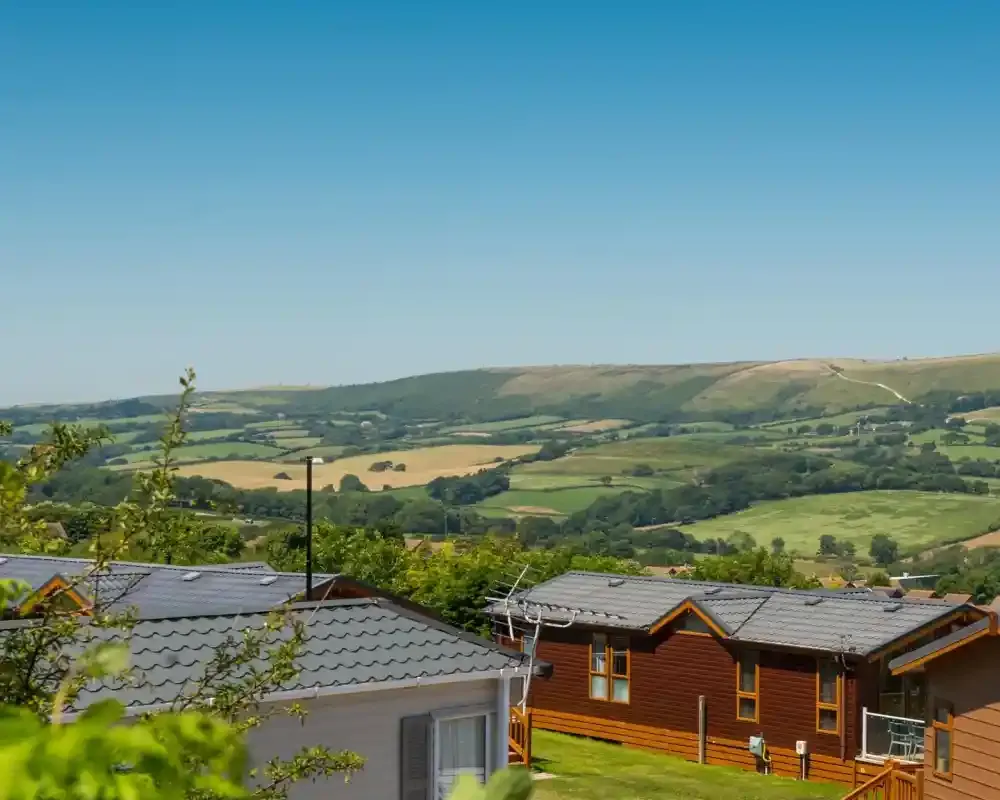 Holiday lodges at Swanage Coastal Park with green fields and the Purbeck hills beyond