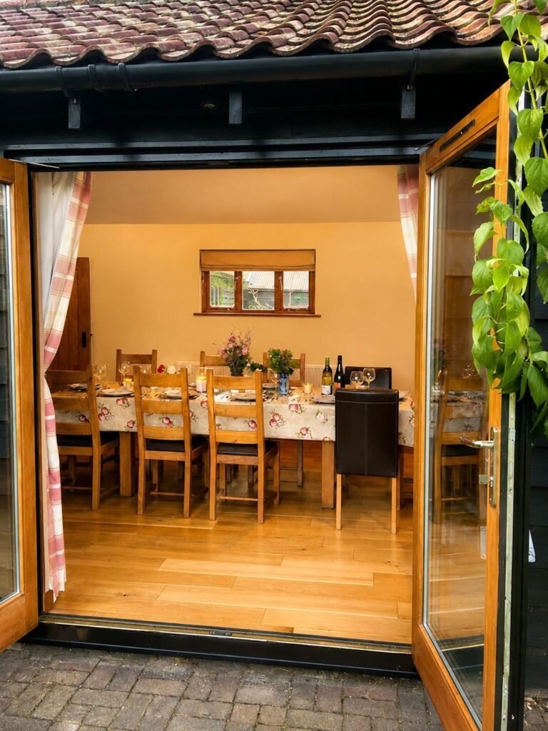 Dining table set for a meal, viewed through open timber doors