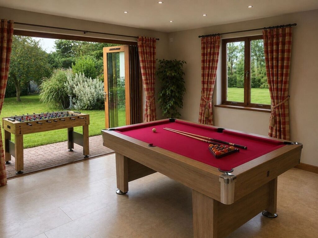 Pool table and table football beside open doors overlooking the garden