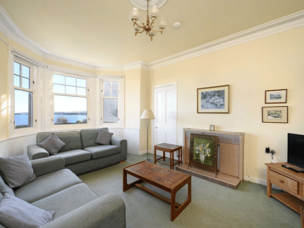 Bright living room at The Beacon in St Abbs with two sofas, television, fireplace and bay windows overlooking the sea