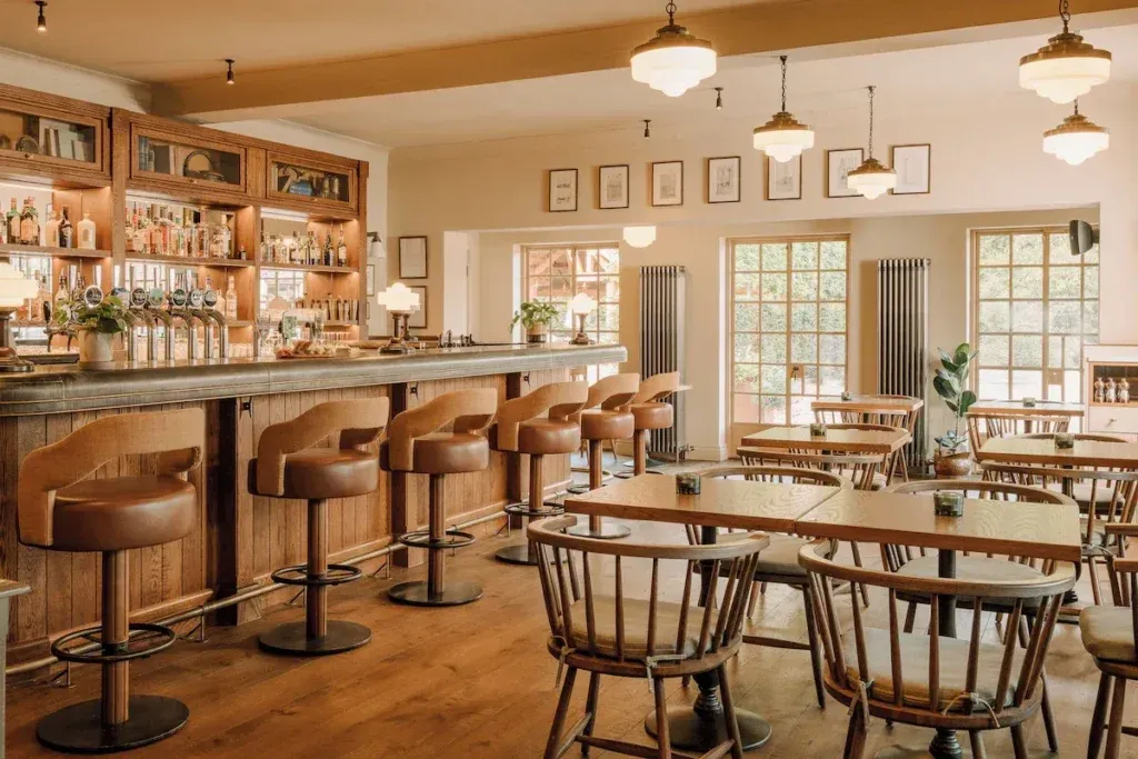 Wooden bar with leather stools, pendant lights and dining tables at The Royal George in Tintern