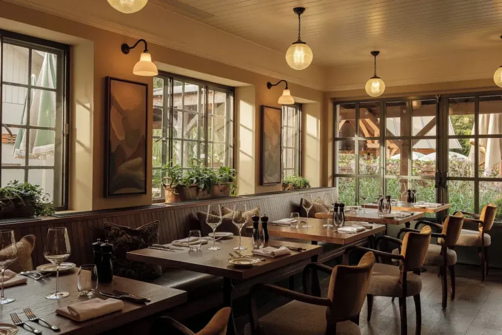 Dining room with set wooden tables, upholstered chairs and large windows at The Royal George in Tintern