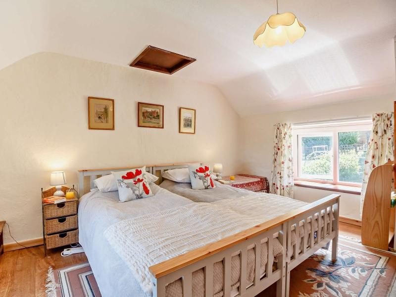 Two single beds positioned together in a bright bedroom with wooden flooring and a garden-facing window
