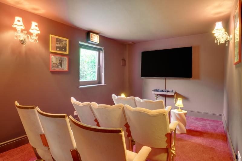 Colourful Cinema House near Craster, Northumberland 3 Home cinema room with vintage tip-up seats, wall-mounted television and warm wall lights