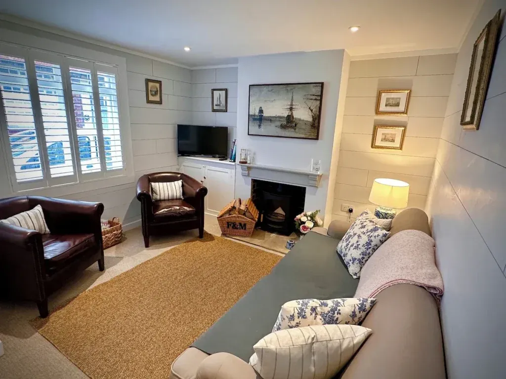 Living room with a sofa, two leather armchairs, nautical artwork and a wood-burning stove