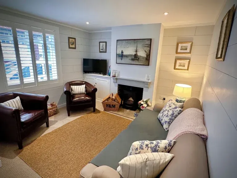 Living room with a sofa, two leather armchairs, nautical artwork and a wood-burning stove