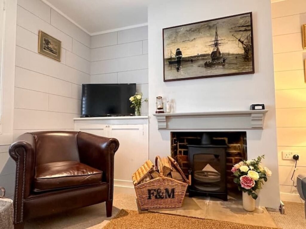 Wind Rose Cottage, Cowes, Isle of Wight 1 Wood-burning stove beside a brown leather armchair and television at Wind Rose Cottage